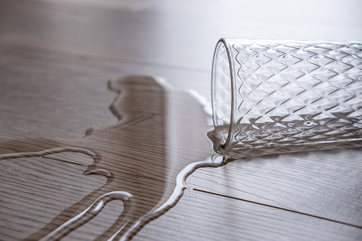 a glass of water spilled onto the floor. Waterproof laminate, concept.